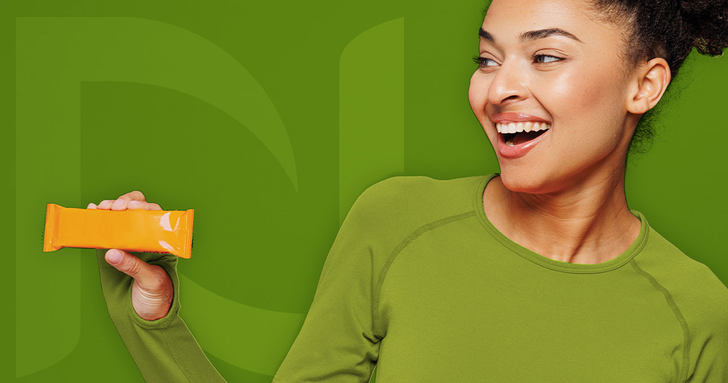 Person wearing a green shirt smiles while holding an orange package against a green background.